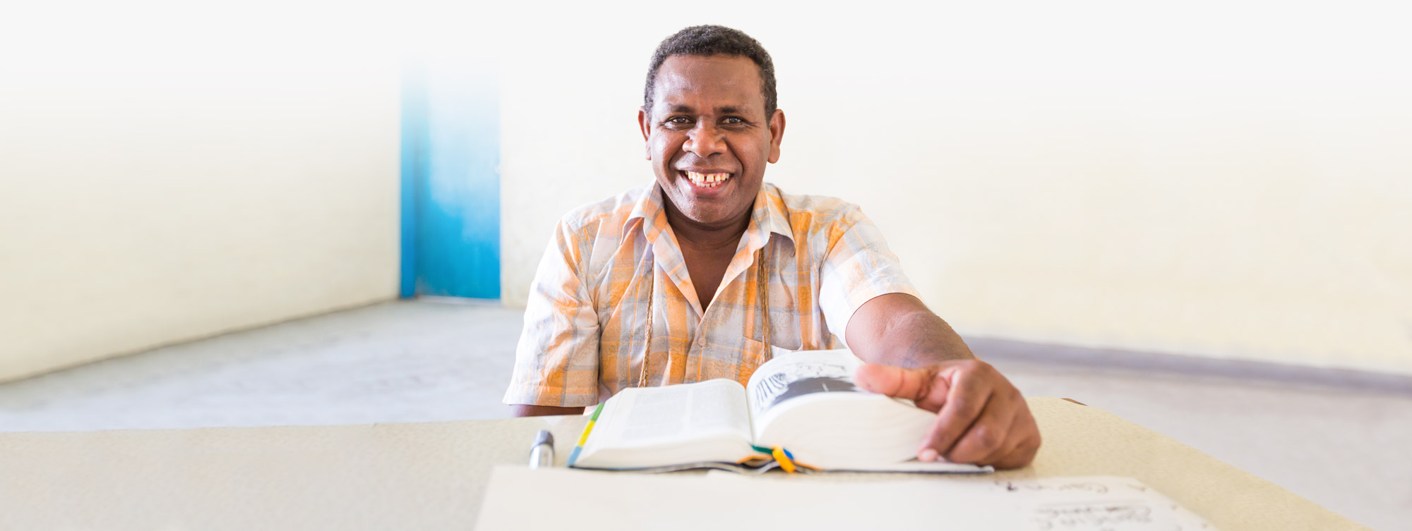 Africa man seated with an open Bible at a table
