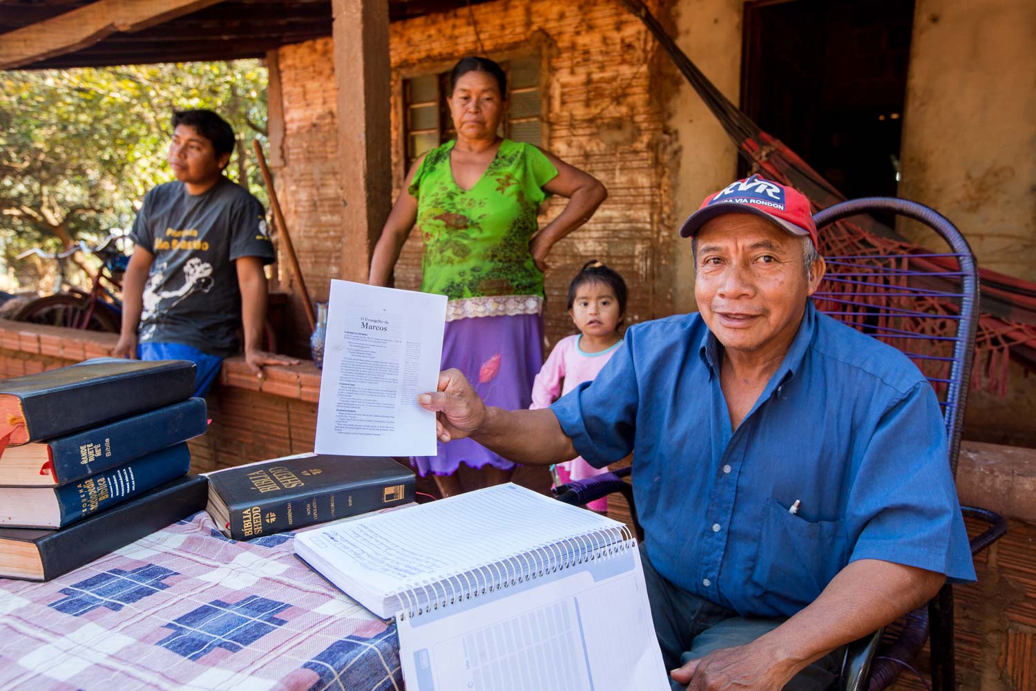 Seated man holds Scripture with family behind him
