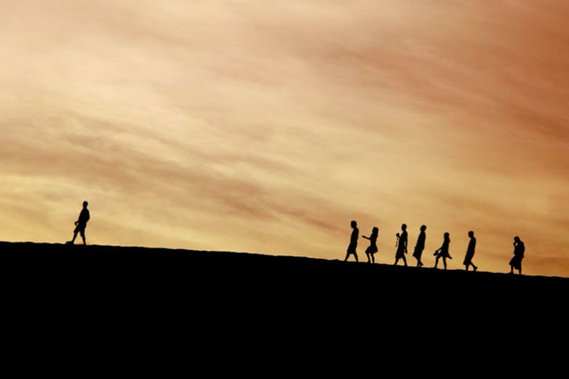 line of people following man on the horizon