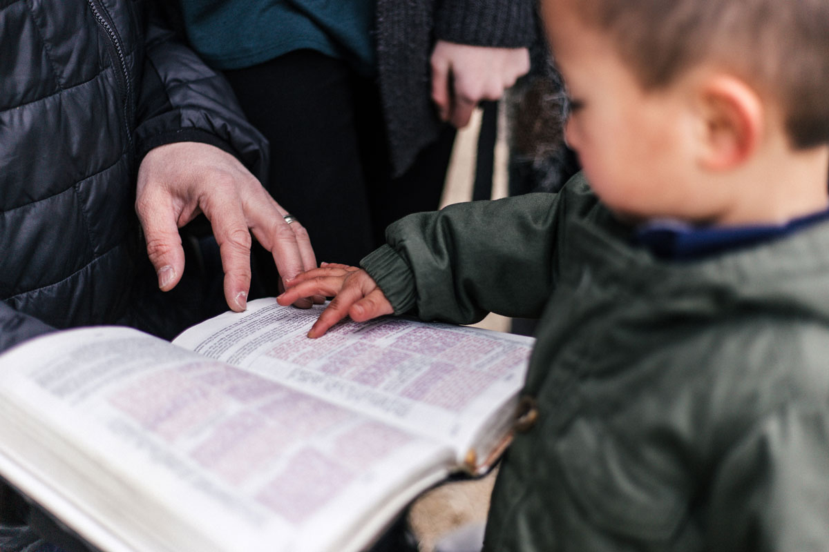 Toddler boy pointing to page in Bible
