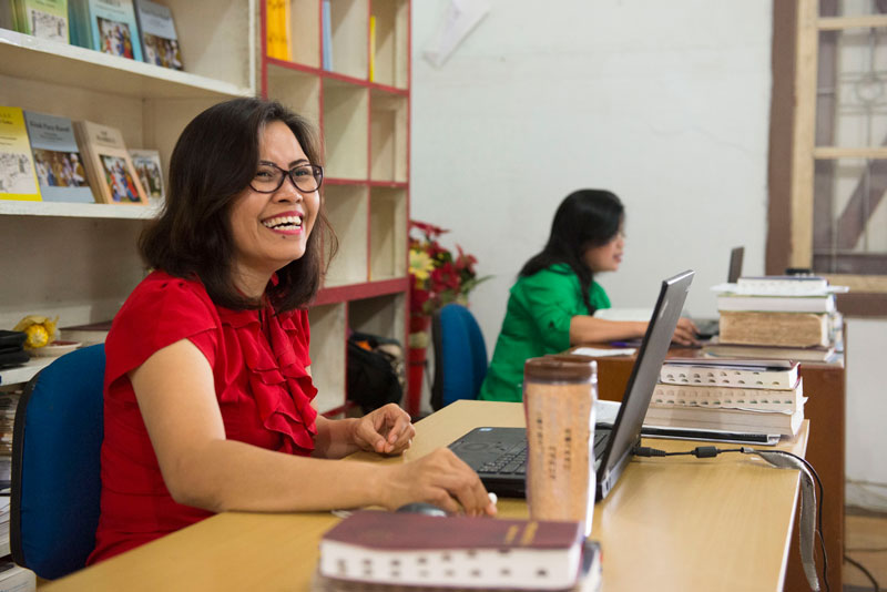 Women sitting at Bible translation work station. 