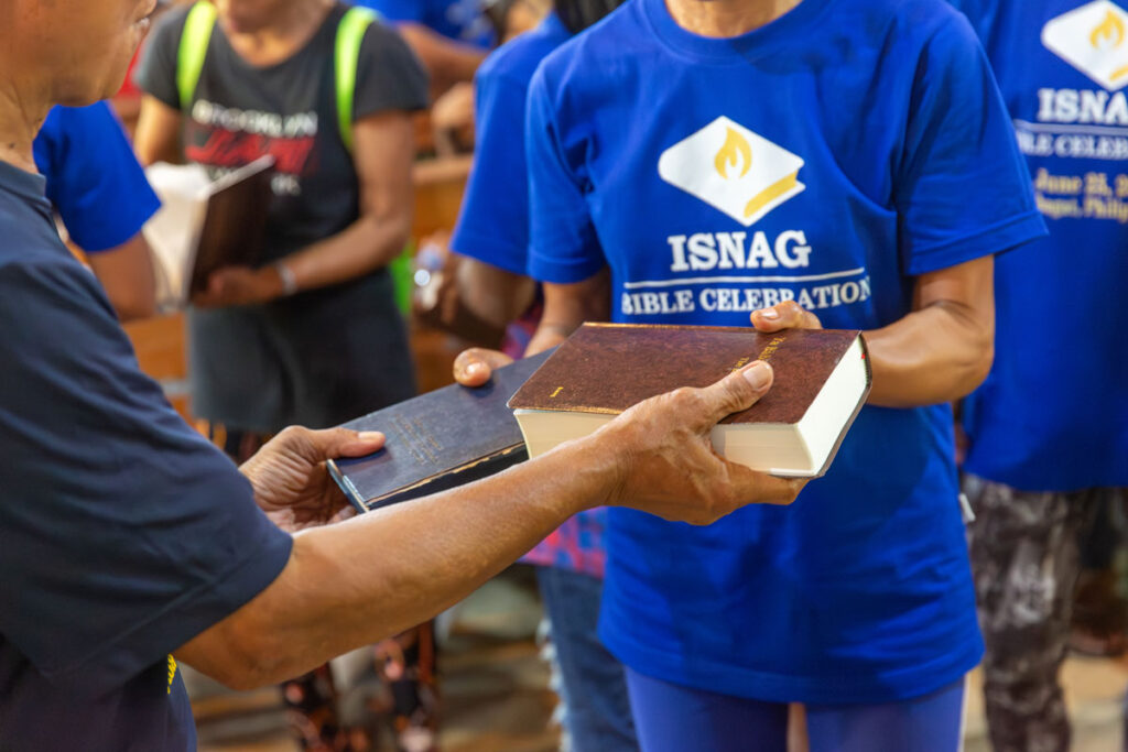 Two people exchanging an old Bible for a new one.