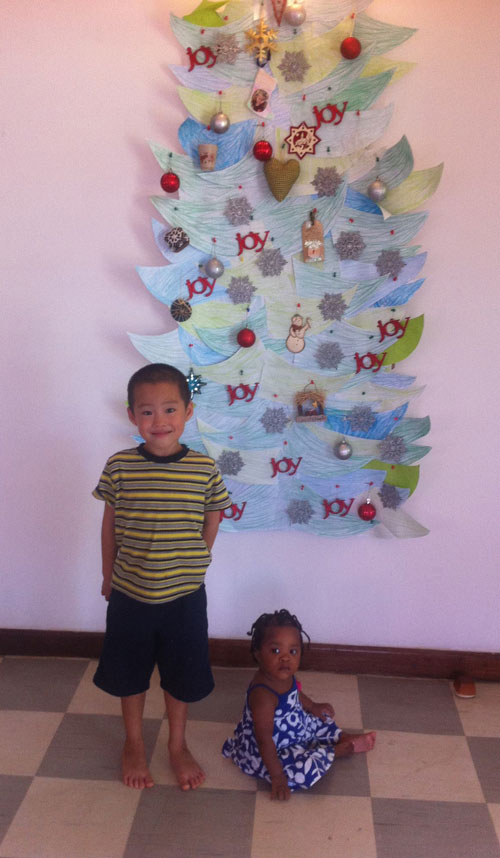 two children in front of a paper christmas tree