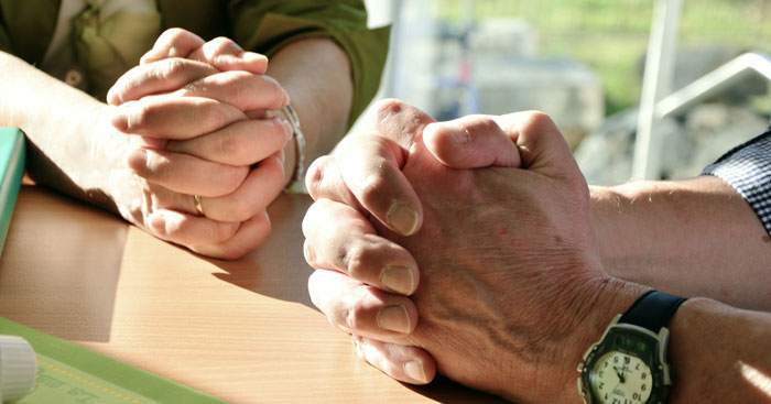 Two pairs of hands folded in prayer.