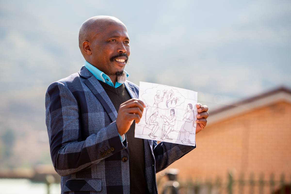 Man from Lesotho holding up a paper with drawn Scripture on it.